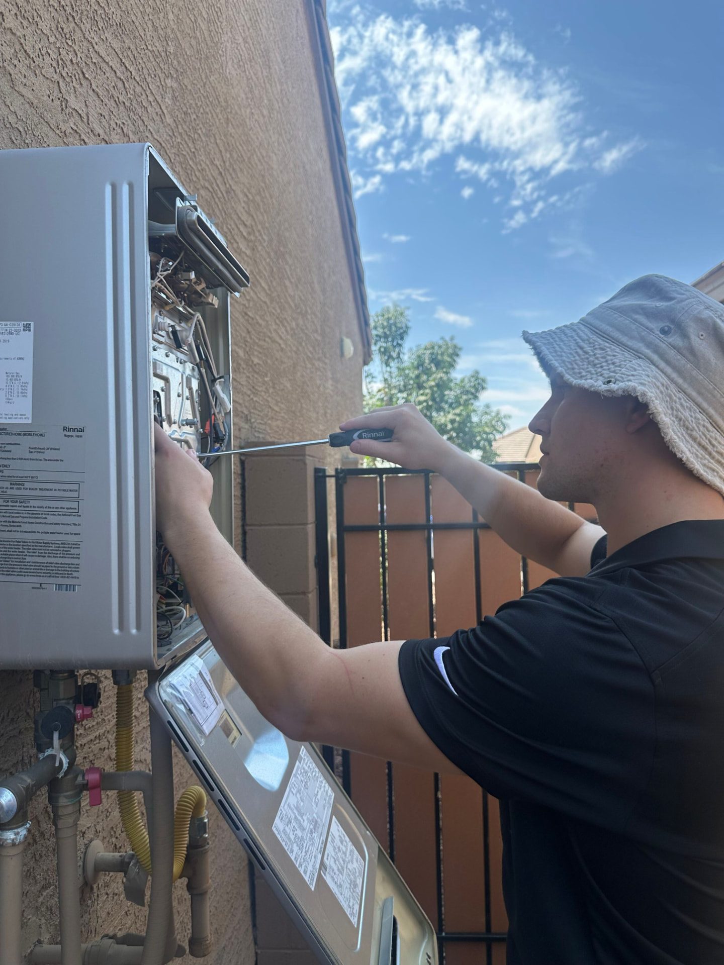 Plumber servicing a residential water heater in a Phoenix garage